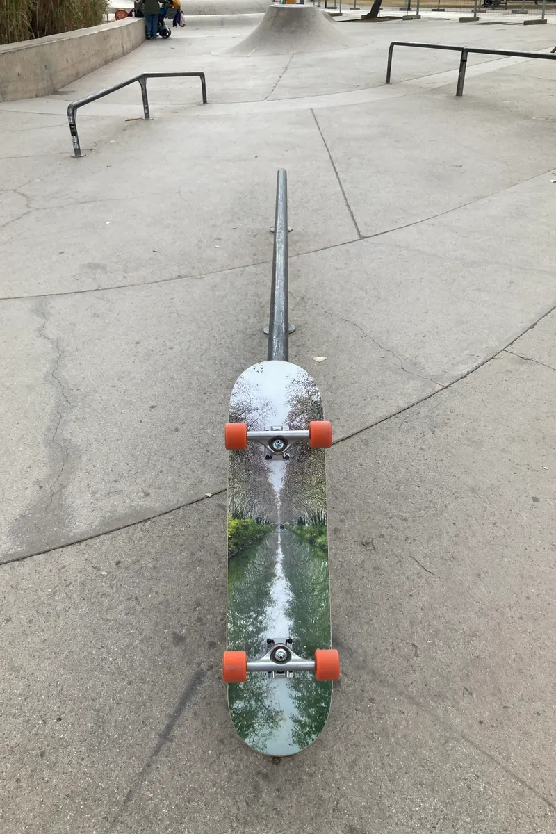 Planche de skate imprimée avec la photo d'un canal, montée avec trucks et roues, dans un skatepark